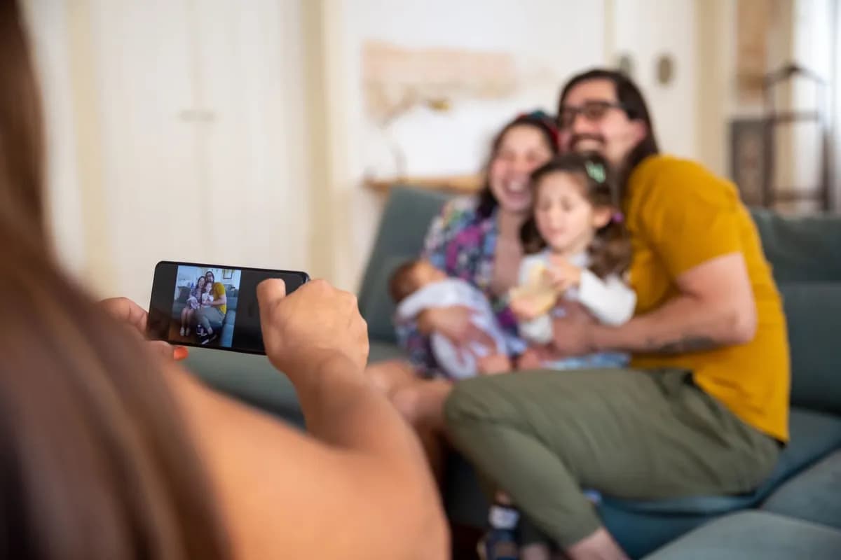 Iemand fotografeert met een telefoon een gezin dat op de bank zit